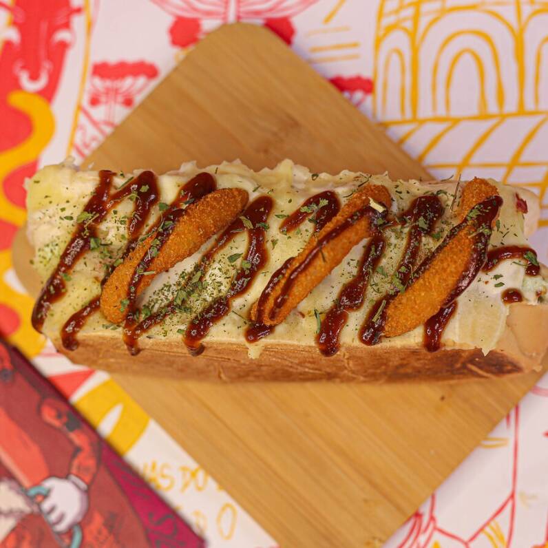 O Sabor mais diferente do cardápio! Combinação mais que perfeita anel de cebola com barbecue! Pão, salsicha perdigão, milho, tomate, cebola, explosão de cream cheese, onion rings, barbecue. Finalizado com aligot (purê de batata com queijo), cream cheese, onion rings, barbecue e cheiro verde. Serve 1 pessoa