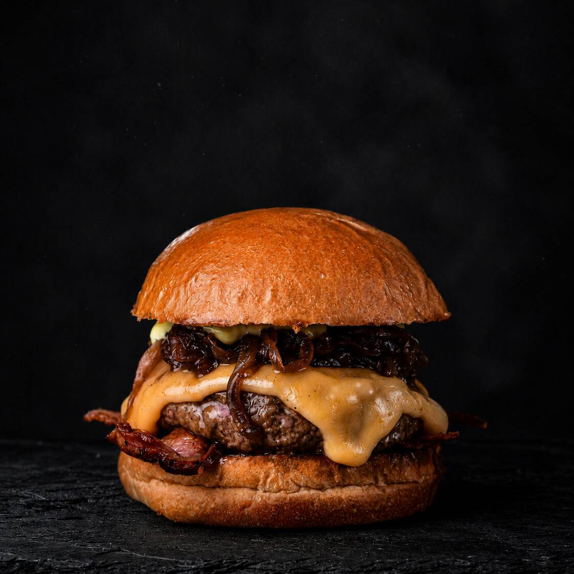 Pão brioche, 180g de alcatra moída com bacon, queijo cheddar, molho especial loyola e cebola caramelizada.