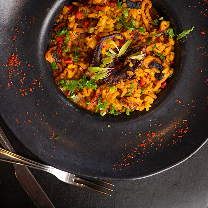 Polvo macio ao limão siciliano servido sobre arroz soltinho. Um prato elegante e cheio de sabor.