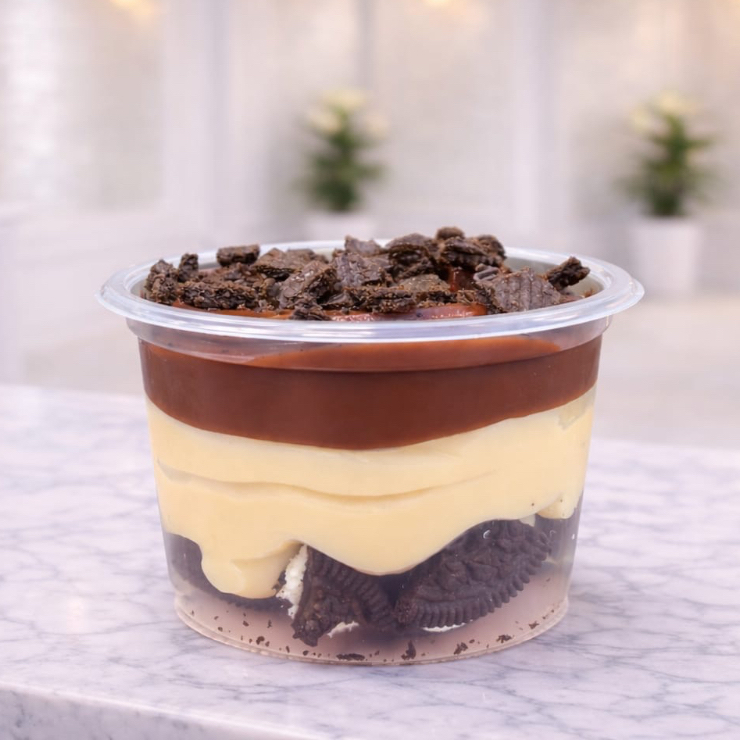 Pedaços de Oreo com uma camada de creme de Ninho e, para finalizar, uma camada de creme de chocolate com farelo de Oreo por cima