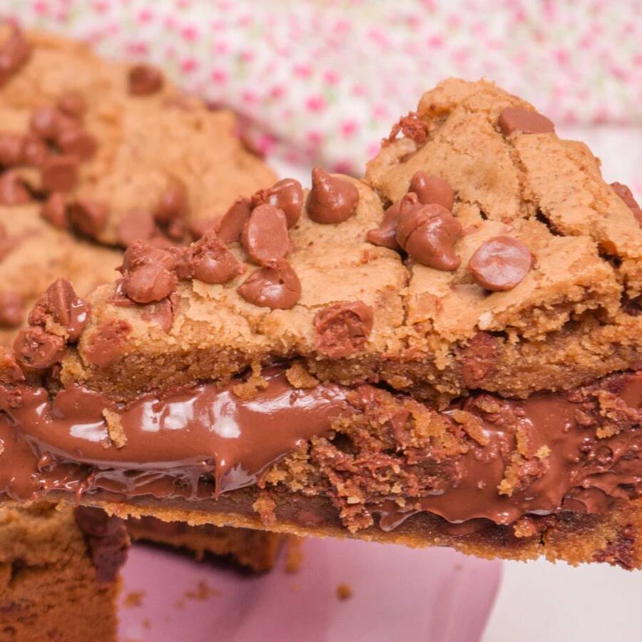 Cookie artesanal douradinho, cheio de gotas de chocolate e com generoso recheio cremoso de Nutella que derrete por dentro. Crocante por fora, macio por dentro e simplesmente irresistível para quem ama chocolate!