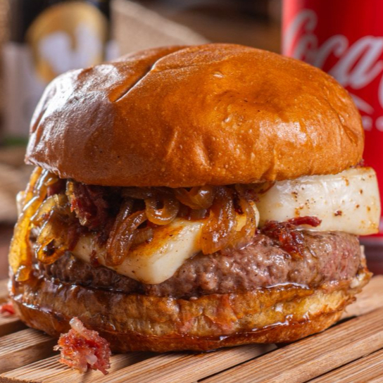 Pão brioche selado, blend bovino 150g, charque desfiada, queijo coalho, mel de engenho e cebola caramelizada.