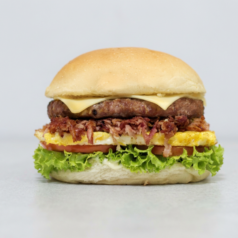 Pão com gergelim, carne de hamburguer, queijo ; bacon em cubos, ovo ,alface e tomate e molho.