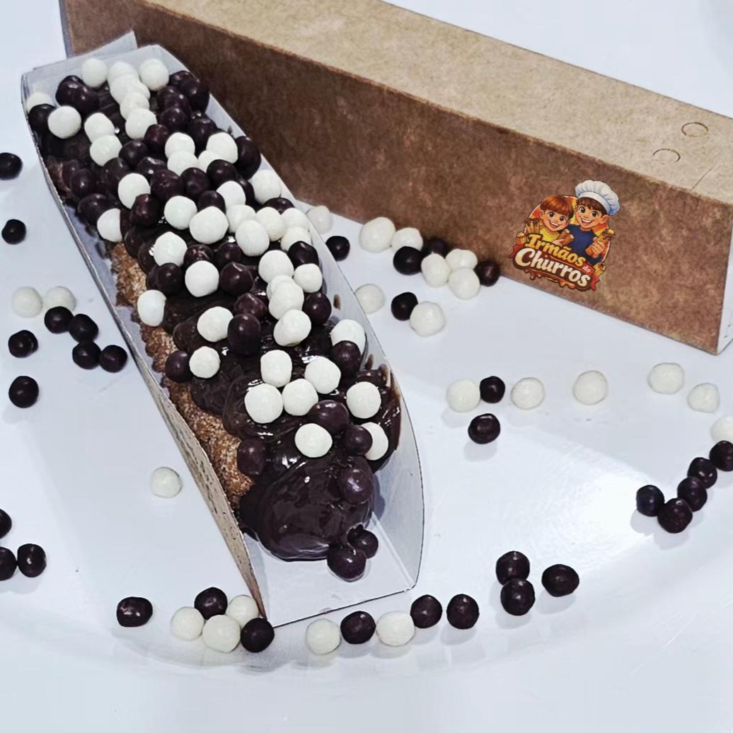 Delicioso Churros salpicado com açúcar de confeiteiro e canela em pó com recheio e cobertura de chocolate com choco ball.