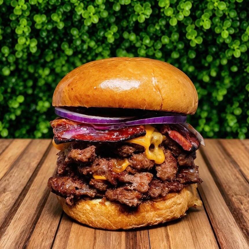 O exagero na medida certa! São 4 suculentos discos de carne (75g cada), prensados na chapa bem quente até criarem aquela crostinha caramelizada (smash real) que você respeita. Entre as camadas, o dobro de cremosidade com fatias generosas de queijo cheddar derretido bacon cebola roxa. Tudo isso abraçado por um pão brioche na manteiga, extremamente macio e brilhante. É para quem não tem medo de ser feliz (e de se sujar um pouco).