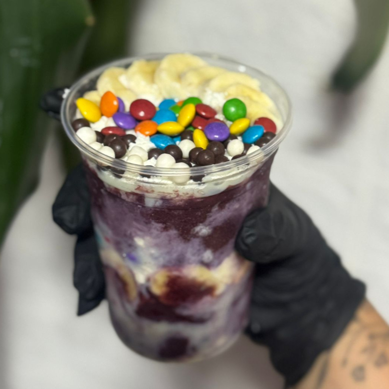 Você manda aqui. Escolha 4 acompanhamentos grátis do nosso cardápio e a gente monta do seu jeito. Banana, morango, leite condensado, amendoim, paçoca, chocoball, confete, leite em pó — cada combinação vira um copo único, do seu gosto, feito pra você. Porque o melhor açaí é aquele que tem a sua cara.