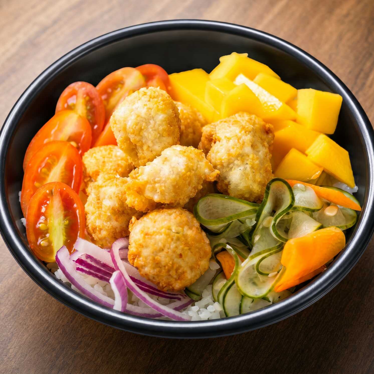 Arroz japonês, frango empanado, salada sunomono, cebola roxa, tomate cereja e manga.