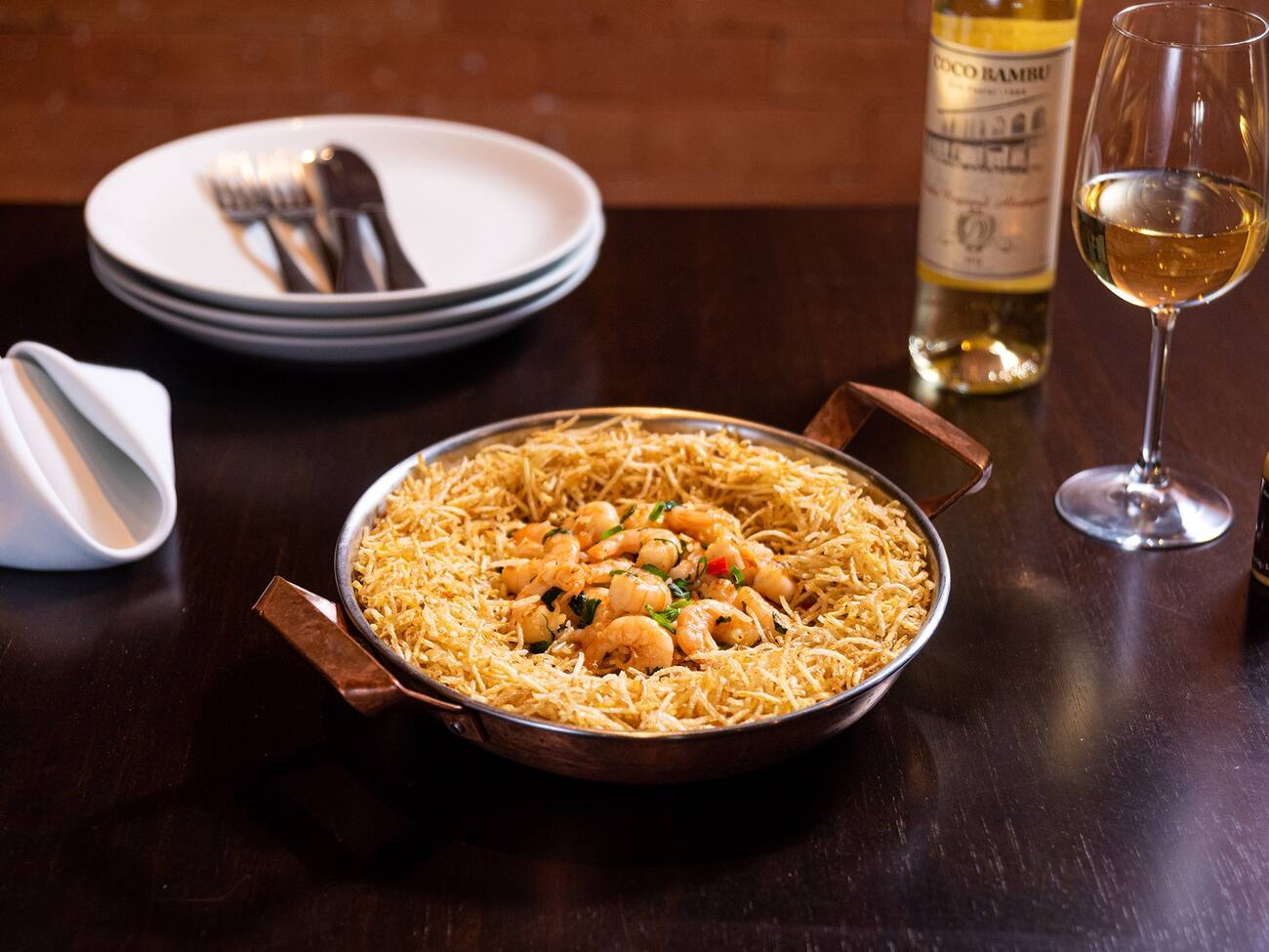 Camarões salteados no azeite com alho, cebola, pimentão, coentro e tomate. Servidos sobre arroz regado com um toque de leite de coco e batata palha.