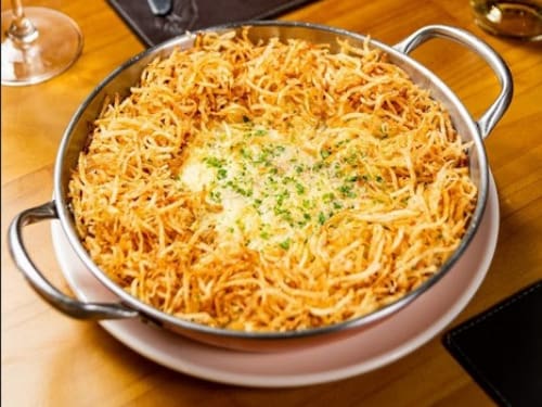 Camarões servidos sobre cremoso arroz com ervilhas e presunto, envolvido com molho branco. Gratinado com queijos mussarela e parmesão. Acompanha batata palha.