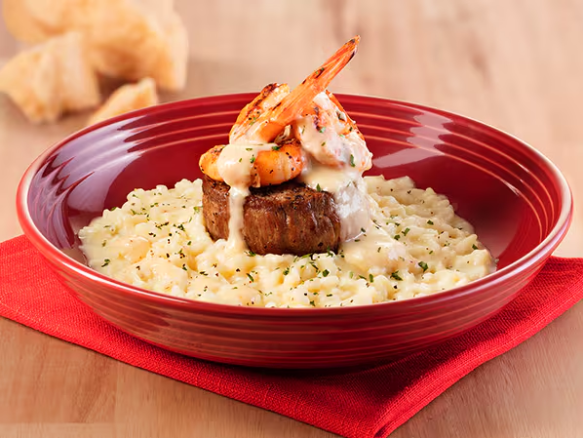 Filet mignon grelhado com cerca de 115 g e camarões grelhados, acompanhados de um saboroso risotto finalizado com molho cremoso de limão-siciliano e parmesão.