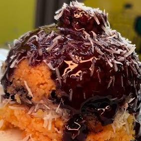 Cuscuz recheado com chocolate e coco, coberto com chocolate e raspas de coco fresco