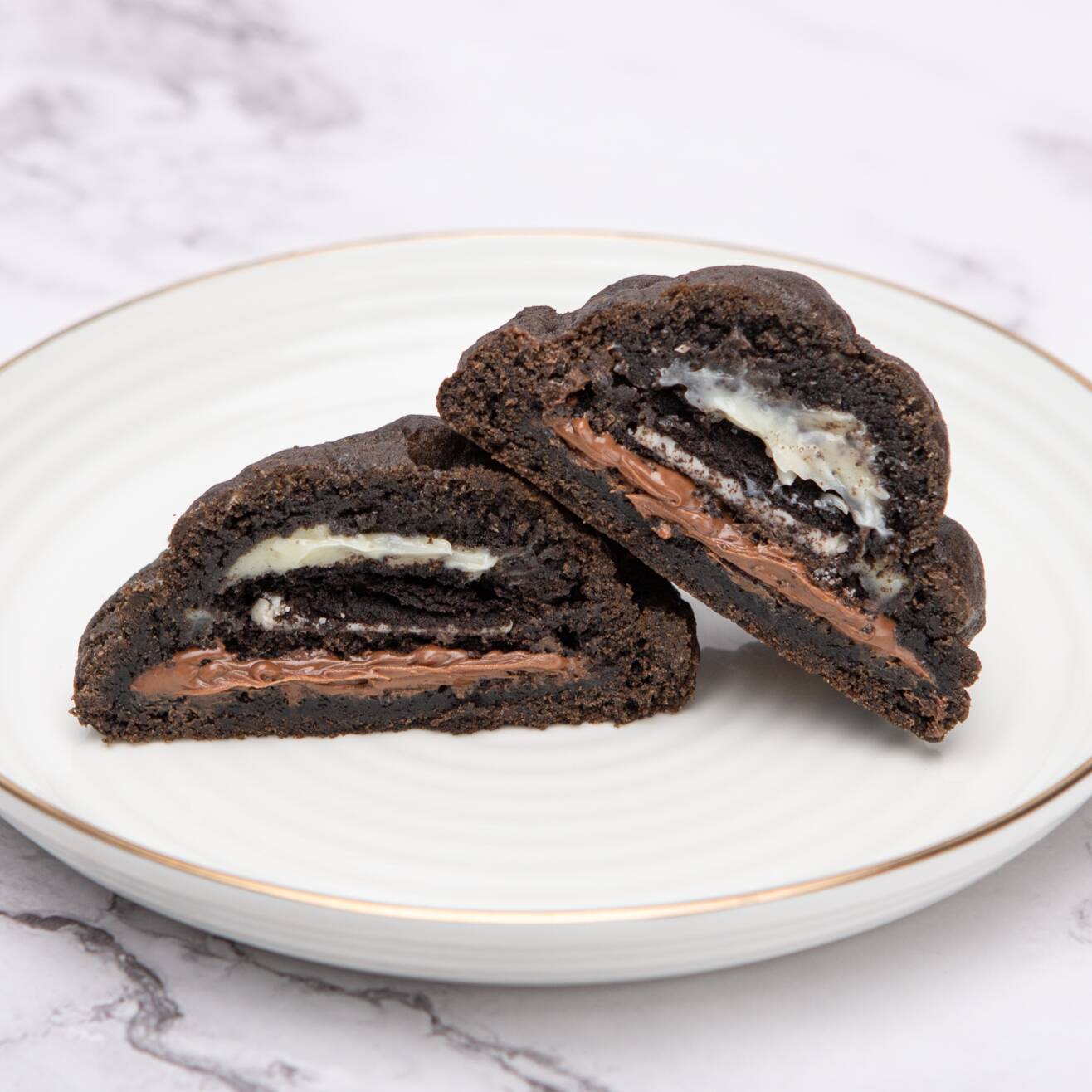 Um cookie feito com massa amanteigada de cacau black, recheado com creme de avelã, brigadeiro de Ninho e um toque crocante do Oreo. Intensamente chocolatoso por fora e cremoso por dentro.