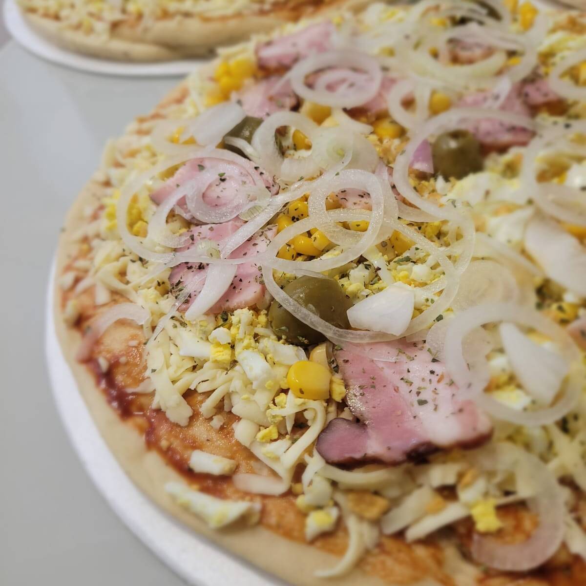 Extrato de tomate, alho, milho, ovos, bacon, cebola roxa, azeitona preta, orégano, muçarela.
Pizza média (30cm).
A pizza vai montada conforme a descrição. Não é possível alterar os ingredientes.