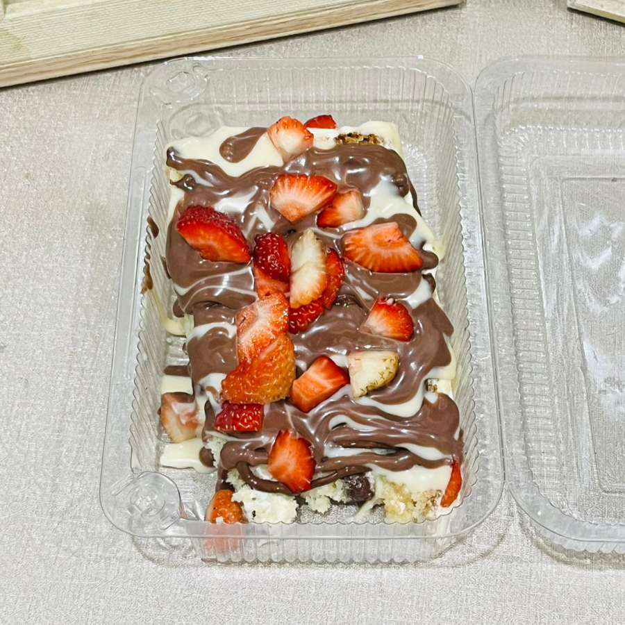Fatia de massa de baunilha com recheio de brigadeiro cremoso de ninho e Nutella, finalizada com pedacinhos de morangos frescos. Tem opções de calda. Serve 1 pessoa.