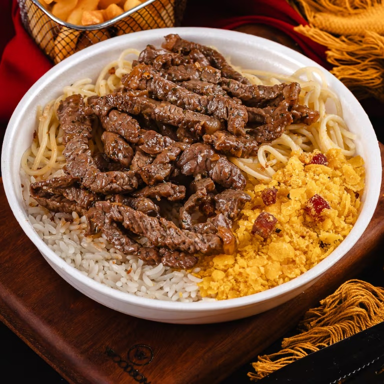 Arroz soltinho, feijão bem temperado, macarrão alho e óleo, farofa crocante, purê cremoso e tiras de carne suculentas.