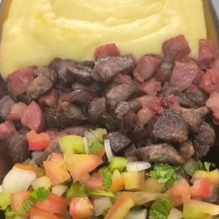 Purê de aipim cremoso cobrindo um recheio de carne do sol desfiada e calabresa bem temperada. Uma combinação caseira, intensa e cheia de sabor.