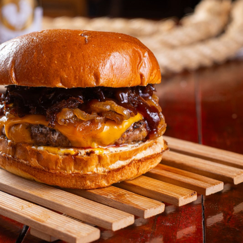 Pão brioche, blend bovino 150g, cheddar, costela bovina desfiada, cebola caramelizada e molho barbecue.