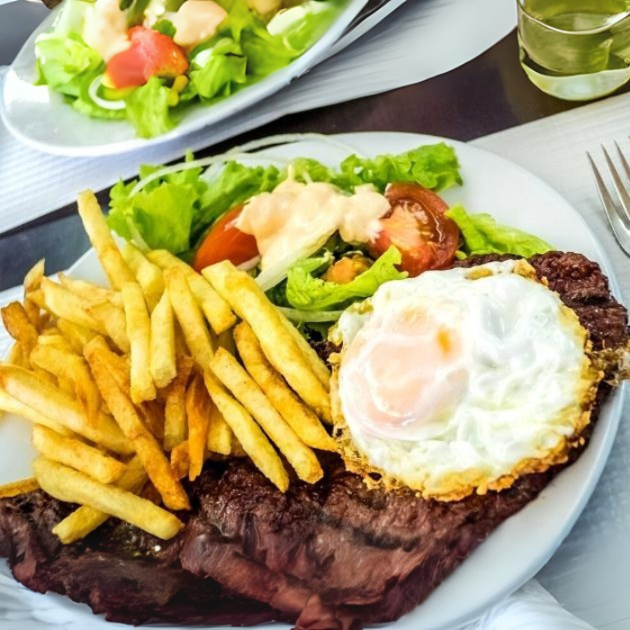 Aproveite 35% de desconto na Marmita Econômica de Bife à Cavalo! Com arroz branco soltinho, feijão carioca bem temperado, um bife suculento, ovo frito no ponto perfeito, batata frita crocante, farofa especial da casa e a salada fresca do dia.