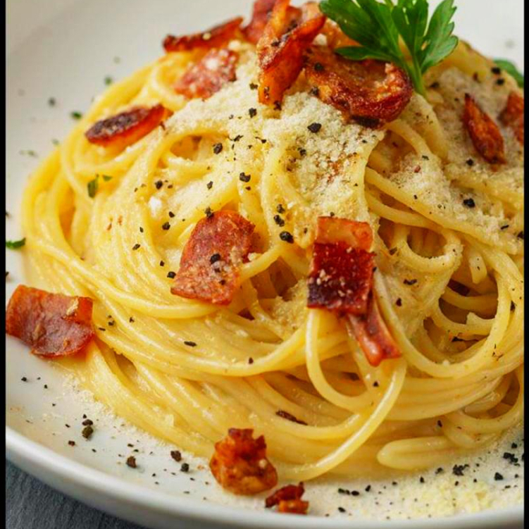 Spaghetti al dente envolvido ao molho cremoso de ovos e queijo parmesão, bacon crocante.