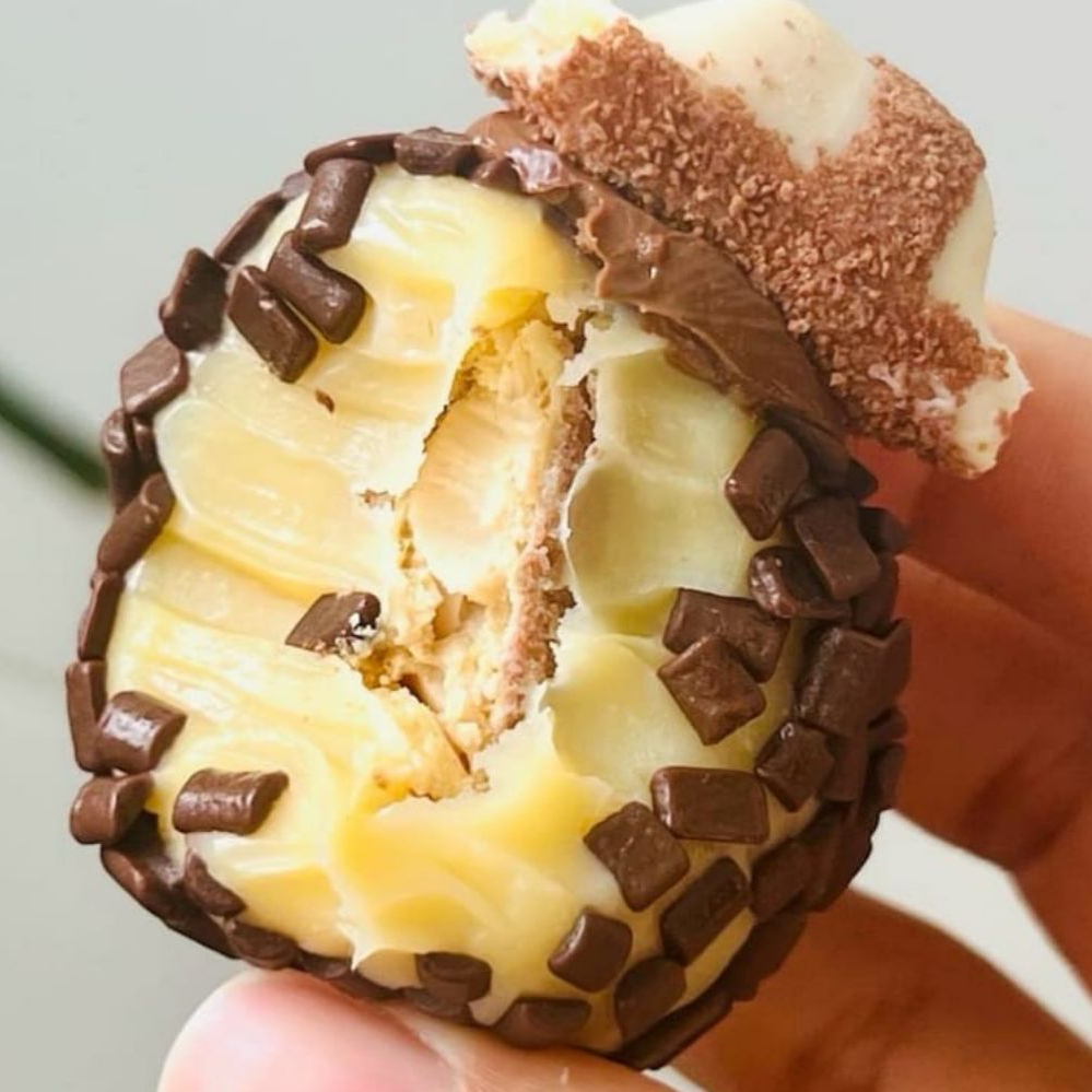 Pedaço de kinder envolto em brigadeiro branco e finalizada com granulados de chocolate nobre e pedaço de kinder white