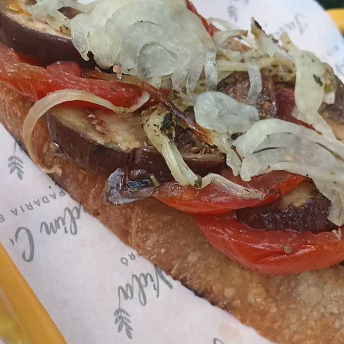 Fatia de Sourdough tostada no azeite, berinjela, tomates e cebola grelhados e molho cremoso de limão com hortelã