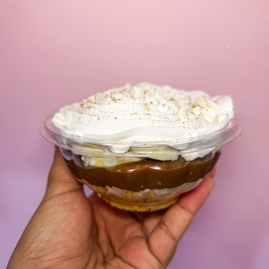 biscoito triturado, doce de leite, rodelas de banana, chantilly e canela em pó no topo