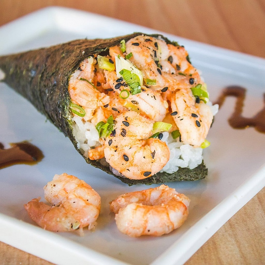 Formato de cone, enrolado à mão com alga nori, recheado com arroz temperado, com camarão pré cozido e outros ingredientes como cream cheese, cebolinha.