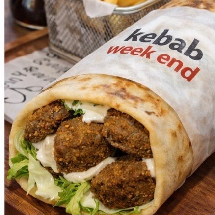 Sanduíche no pão integral com bolinhos de falafel, alface crocante, tomate e molho tahine.