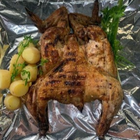 Frango assado na brasa, acompanhado de um deliciosa porção de batata no molho de alho e farofa.