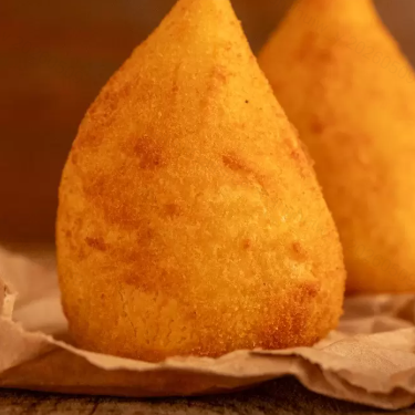 Uma deliciosa combinação de massa crocante recheada com suculento frango desfiado . Feita com ingredientes frescos e selecionados, para garantir a máxima crocância e sabor. Perfeita para saborear como petisco, ou mesmo como uma refeição rápida e deliciosa. Experimente a nossa coxinha de frango e se apaixone! Venha provar e se deliciar com essa maravilha da gastronomia brasileira.