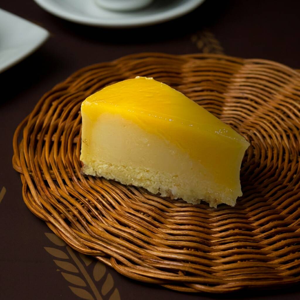 Brilho, sabor e tradição em cada pedaço! Fatia de quindim artesanal, preparada com coco ralado e gemas frescas, resultando em uma textura cremosa e superfície dourada e reluzente. Doce na medida certa, com aquele sabor clássico que derrete na boca e conquista desde a primeira colherada. Ideal para sobremesas, festas ou para acompanhar um café especial. • Ingredientes principais: coco ralado, gemas, açúcar, manteiga e leite de coco. • Diferencial: receita artesanal com coco fresco e preparo cuidadoso que garante brilho, cremosidade e sabor autêntico. • Alergênicos: contém leite e ovos. Pode conter traços de glúten.