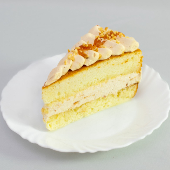 Fatia de torta de massa de pão de ló, creme de cupuaçu e coberta com doce de leite e amendoim