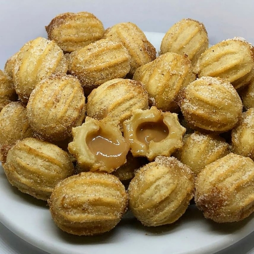 Mini churros é um doce frito com massa levemente doce e recheio de doce de leite cremoso. A casca é crocante e dourada, e o interior é macio e aveludado. Polvilhado com açúcar e canela.