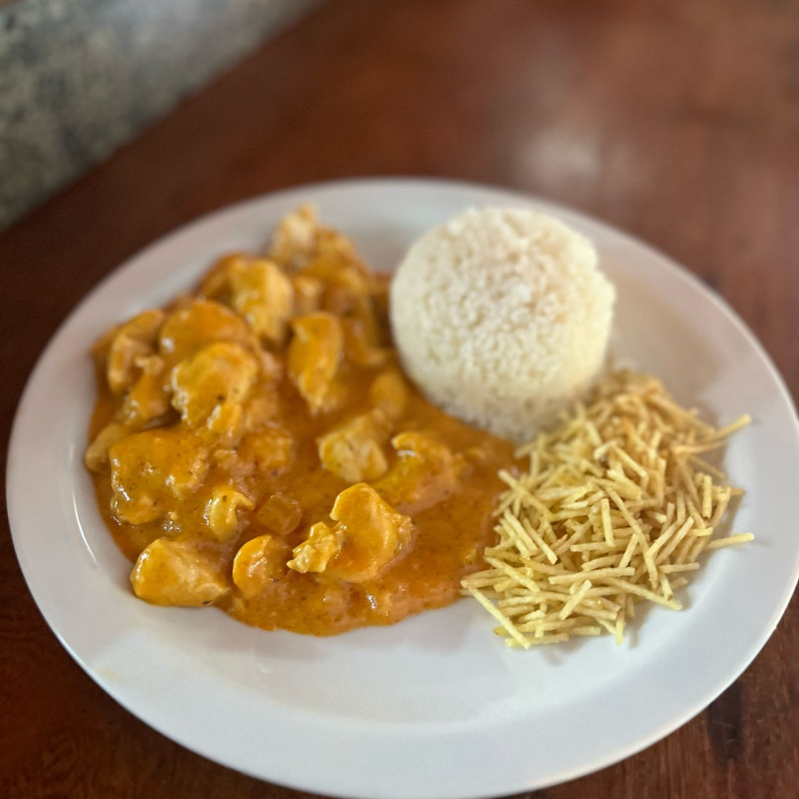 Frango macio em um molho cremoso e saboroso, servido com arroz branco e batata palha crocante.