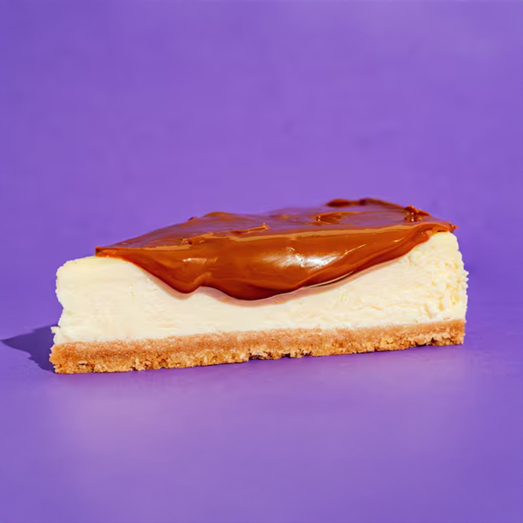 Cheesecake Navarro Doce de Leite com massa suave e amanteigada, acompanhada de uma calda generosa de doce de leite servida à parte.