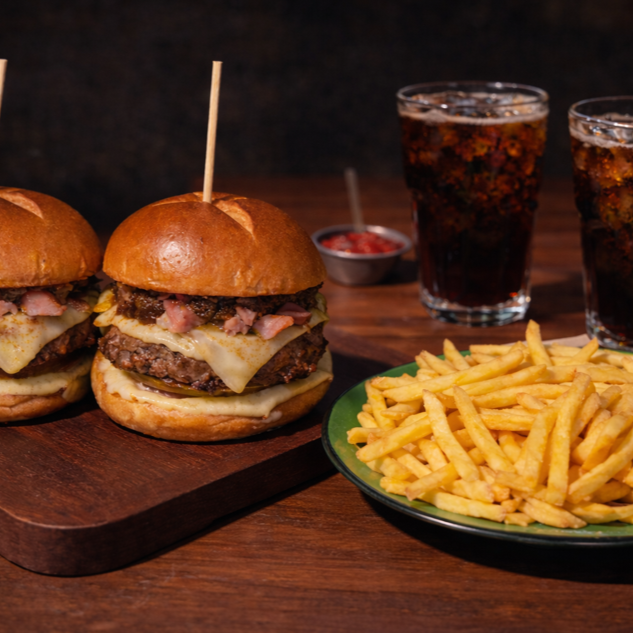 02 Hambúrgueres Glorioso Bacon: Pão especial selado na manteiga, burger bovino 160g, Mussarela derretida no fogo forte, bacon artesanal, maionese defumada de ervas (feita na casa), tomate, Geleia de cebola caramelizada (feita na casa). 1 Batata G (450g), quentinha, crocante e sequinha. 2 Refrigerantes (350ml), escolha o sabor.