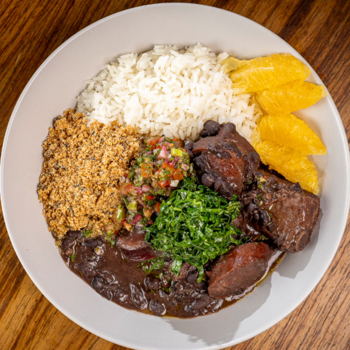 Clássicos da feijoada em porção ideal: carnes nobres, couve no alho, arroz branco e farofa de mandioca. Finalizada com laranja fresca e vinagrete de coentro, cebola roxa e pimenta dedo de moça