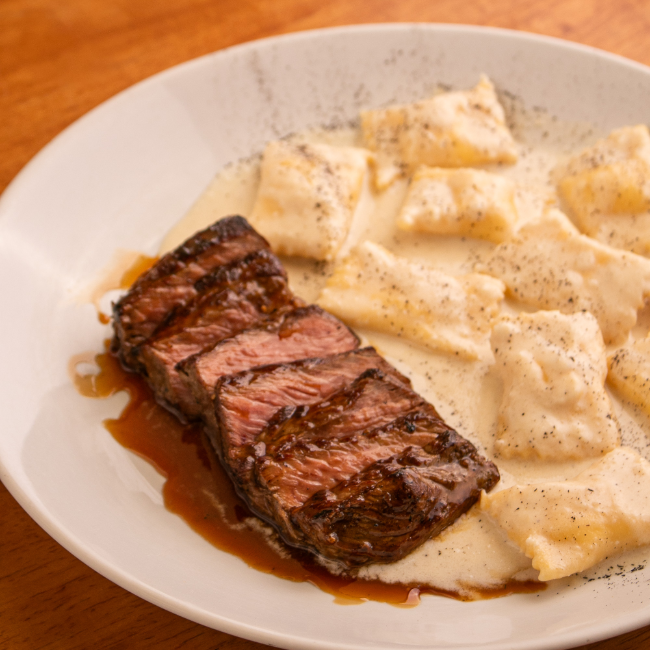Ancho Grelhado servido com Molho Roti, Agnolotti de Queijos Brasileiros, Pangrattato de Pão de Queijo e Laranja Bahia, finalizado com Azedinha Frita.