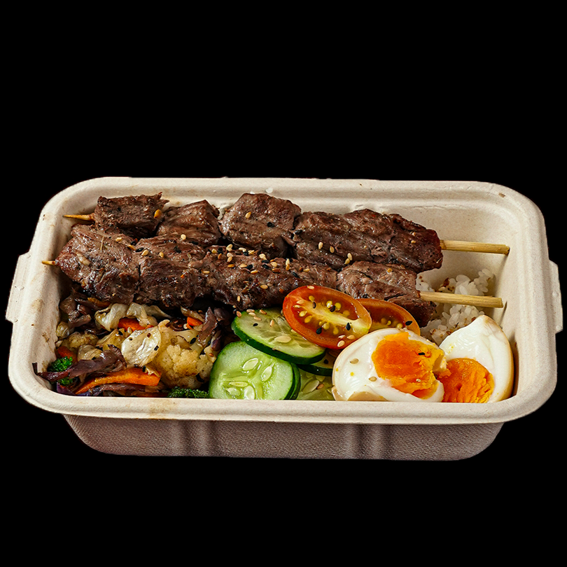 Uma combinação equilibrada e cheia de umami da culinária japonesa. Gohan quentinho finalizado com furikake (tempero japonês à base de gergelim e algas que traz sabor e crocância), espetinho de filé mignon, pepino fresco, ovo marinado com gema mole e legumes no vapor — brócolis, couve e repolho roxo — finalizados com cebolinha. Molho sugerido: Tarê. ‼️Obs: **Não realizamos troca de nenhum ingrediente do Bentō Filé Mignon Himitsu.