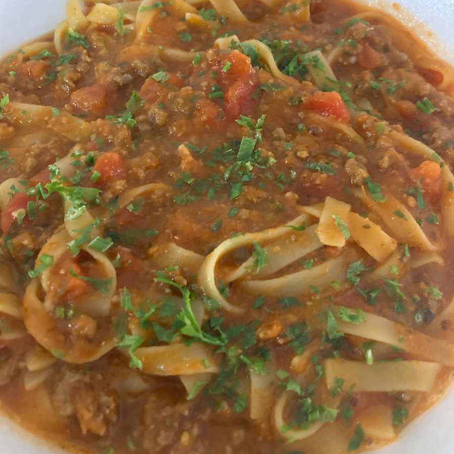 Talharim servido com um rico molho bolonhesa de carne moída e tomates frescos.