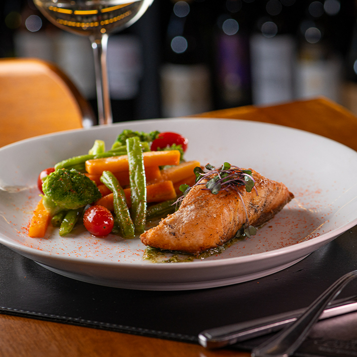 Posta de salmão grelhada servida com legumes salteados no azeite e ervas