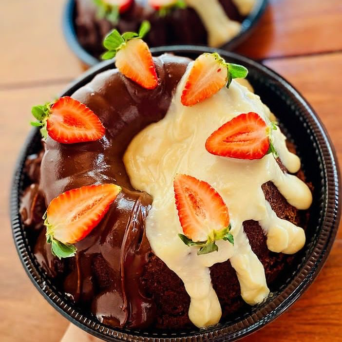 Um delicioso Bolo vulcão com cobertura chocolate e recheio de Leite ninho com Morangos frescos. 800gramas.
