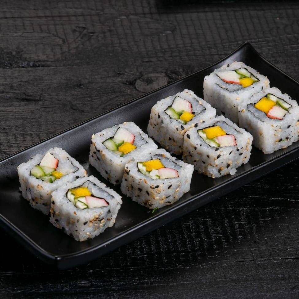 Arroz com gergelim, enrolado em um recheio de manga pepino e kani.