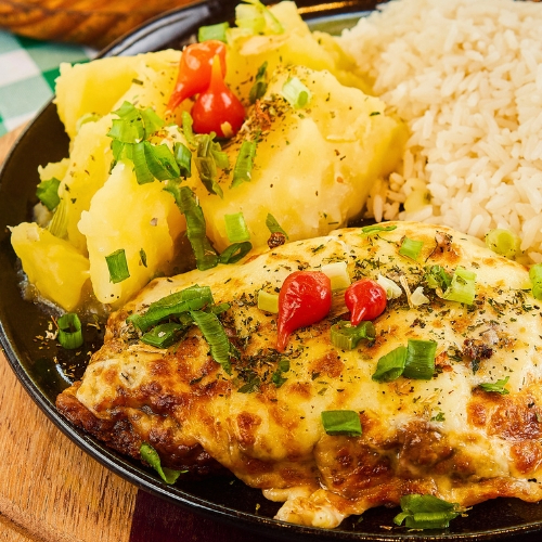 Cupim suculento com crosta crocante de queijo, servido com arroz fresquinho e mandioca cremosa. Um prato completo e delicioso!