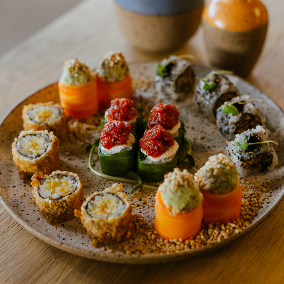 Uma seleção com 4 variedades: gunkan de couve com creme de castanha de caju finalizado com geleia de pimenta vermelho, hot roll de chutney de manga, uramaki de shitake empanado e gunkan de cenoura com creme de alho poró com xerém de castanha de caju.