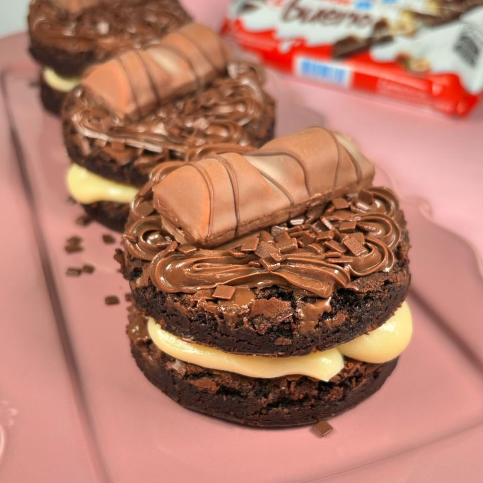 2 rodelas de 10cm cada de brownie, creme de ninho, chocolate no topo com 2 quadradinhos de Kinder Bueno