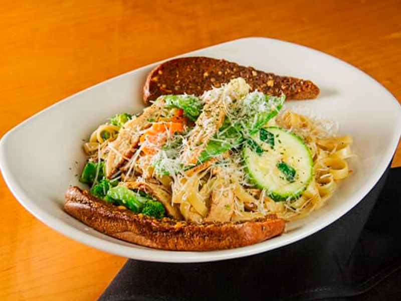 Fettuccine tradicional al dente com legumes e peito de frango grelhado, refogado com um cremoso molho alfredo e coberto com queijo grana padano.