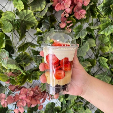 Copo composto por Pedaços de brownie Brigadeiro branco Pedaços de morango fresco Mousse de ninho