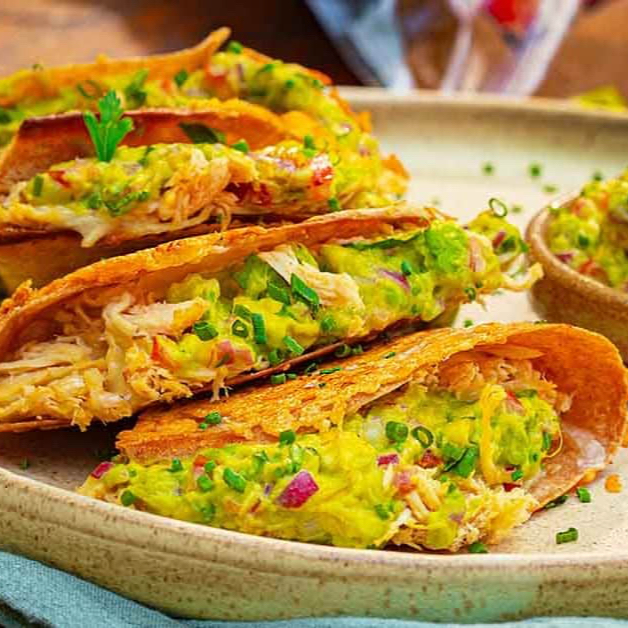 Taco individual recheado com frango desfiado, queijo e guacamole para finalizar.