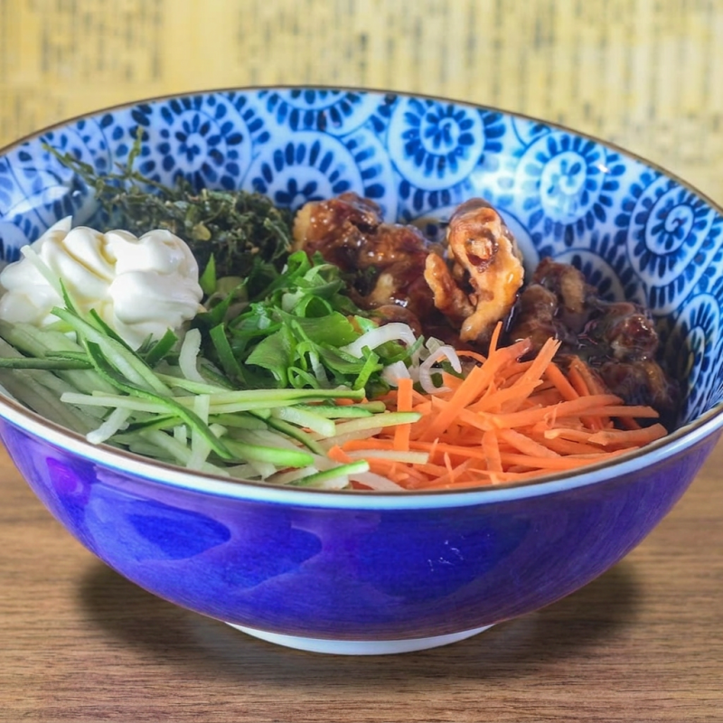 Poke com base Gohan (arroz japonês temperado), bolinhas de frango crocantes com molho teriyaki, cebolinha, pepino em conserva, couve frita, cream cheese e molho teriyaki. Servido com molho da casa